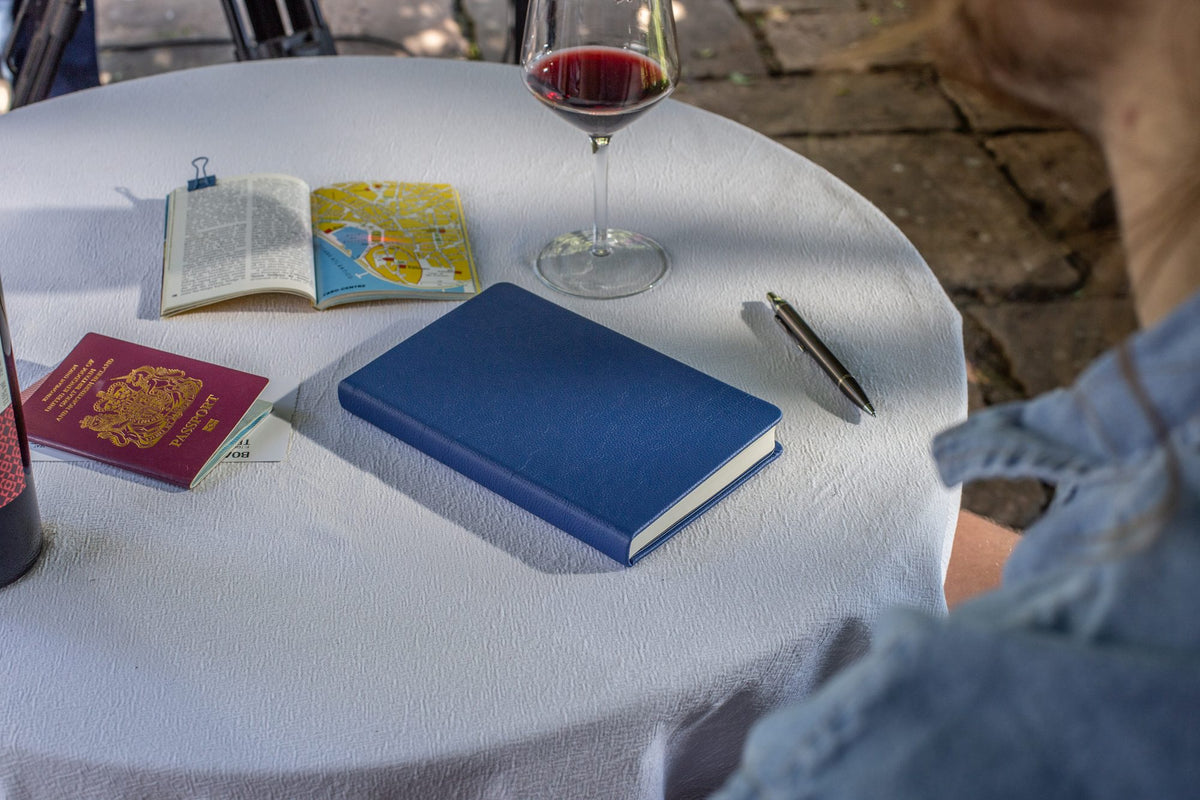 A Pacific Blue Inspire notebook on a café table beside a passport and map